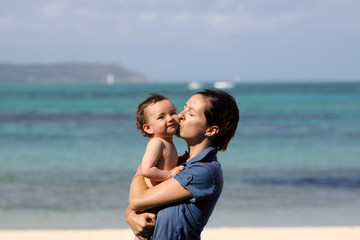 Eine Mutter küsst ihr Kind am Strand von Mauritius.
