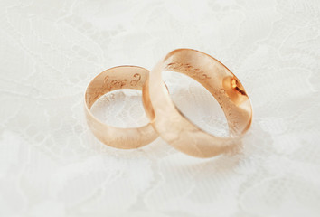Beautiful golden wedding rings with engraving on a white surface