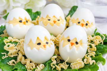 Little chicken in nest, deviled eggs served with salad and dry ramen on white plate, horizontal