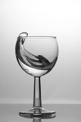Transparent glass cup with a pouring bubbling cold fresh water with bubbles and drops