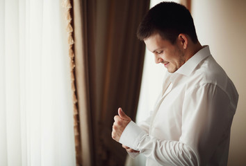 handsome groom getting dressed and preparing for the wedding