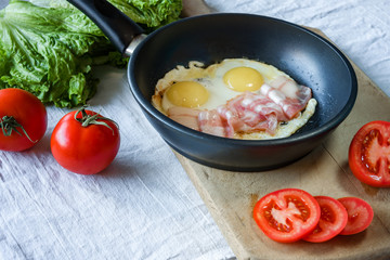 Scrambled eggs and bacon on frying pan on table close-up