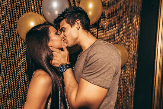 Romantic young couple kissing in the night club