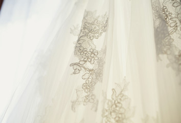 The wedding dress hangs on the hanger