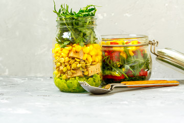 Healthy take-away lunch jars.  Guacamole, corn, tofu, beans, arugula. Paprika, falafel,  dill and corn. Clean eating, vegetarian, raw, detox, dieting concept