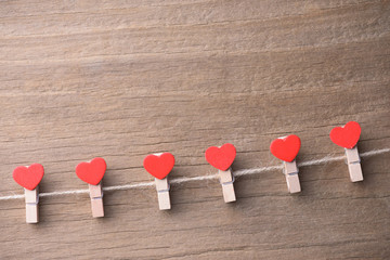 Valentines day concept background.The red  heart shape clothespins hanging on rope with old wood floor background.