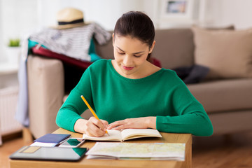 woman with notebook and travel map at home