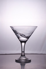 Transparent glass cup with a pouring bubbling cold fresh water with bubbles and drops