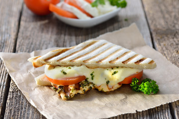 Streetfood: Italienisches Panini mit gegrillter Kräuter-Hähnchenbrust, Tomaten und Mozzarella - Toasted panini with grilled chicken breast fillet, tomatoes and melted mozzarella 