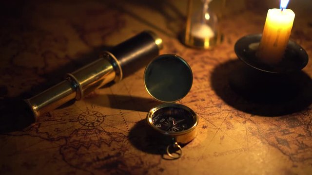 compass and spyglass on old world map in candlelight