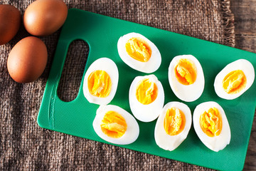 Hard boiled eggs, sliced in halves on cutting board wooden backg
