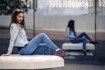Young and attractive woman is sitting on the bench in industrial