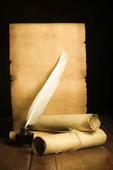 Inkwell with a light pen, rolls of papyrus on the background of old paper developed