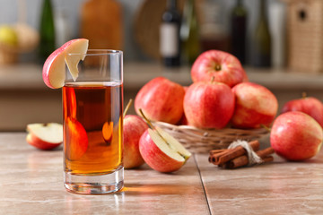 Glass of apple juice and ripe pink apples on a kitchen table