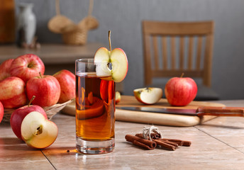 Glass of apple juice and ripe pink apples on a kitchen table