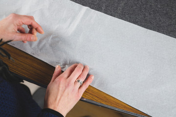 Hands of seamstress fixing template to fabric