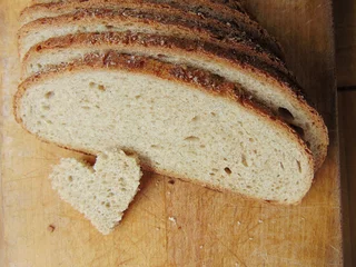 Foto auf Glas Heart shaped piece of bread in front of full bread © melih2810