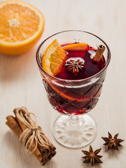 A glass of mulled wine with cinnamon, orange, anise on white woo