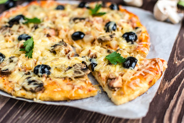 Pizza with meat, mushrooms, pineapple and olives on a wooden background