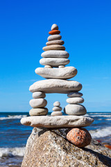High pyramid of white stones balance on the edge of the cliff on the sea background. Concept of harmony and balance