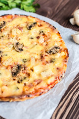 Hawaiian pizza with meat, mushrooms and pineapple on a wooden background