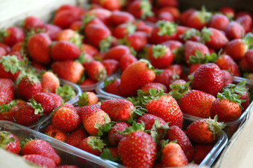 Tasty strawberries in plastic containers on market, closeup