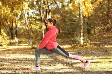 Naklejka na ściany i meble Sporty young woman training in autumn park