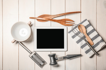 Kitchen utensils with tablet on wooden table