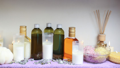 Obraz na płótnie Canvas Bottles of essential oil, sea salt and candles on table