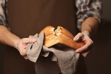 Male hands breaking freshly baked bread, closeup
