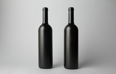 Two wine bottles are standing on gray background