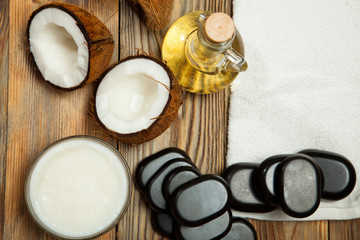 Oil, coconut and stones for a massage on  wooden background