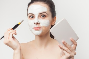 surprised woman with make-up brush, cleansing mask