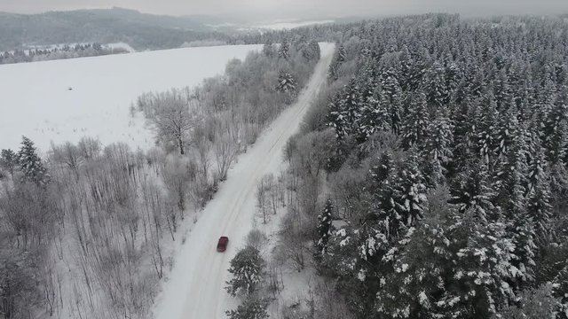 Car driving through snowy pine forest in winter