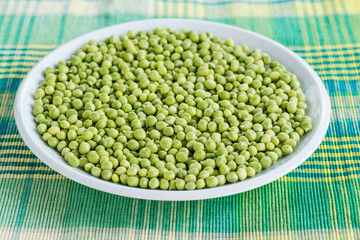 Fresh green peas in a ceramic bowl on table.