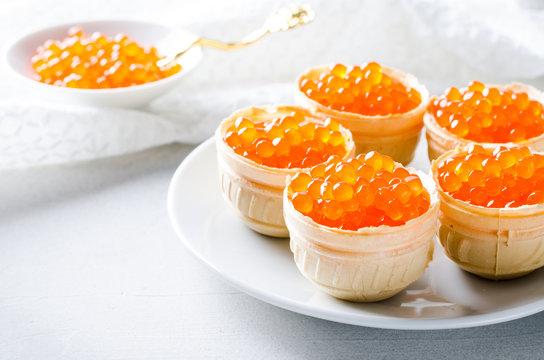 Red caviar tartlets, appetizer canapes on bright background