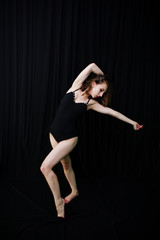 Girl dancer jumping and dancing on a black background. Studio sh