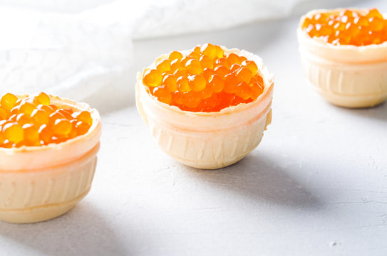 Red caviar tartlets, appetizer canapes on bright background