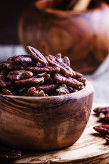 Raw pecan nuts in wooden bowl, rustic style, selective focus