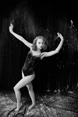 Girl dancer jumping and dancing in the white dust with flour on