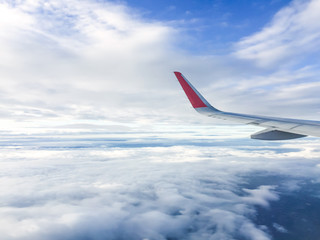 Wing of airplane flying above the clouds in the sky