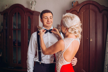 Mother is helping with a bow-tie to her son before wedding ceremony. Concept mother and son.