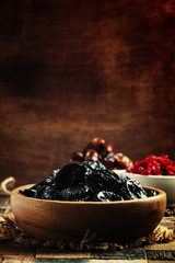 Prunes in wooden bowl, rustic style, selective focus