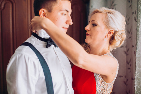 Mother is helping with a bow-tie to her son before wedding ceremony. Concept mother and son.