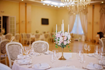 Guest tables with candlestick in rich decorated wedding banquet room