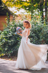Obraz na płótnie Canvas bride with flowers in hand outdoor. Blond woman circle wedding dress.
