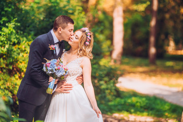 Portrait of kissing newlyweds. Bride and groom in the park. Dancing couple on the nature.