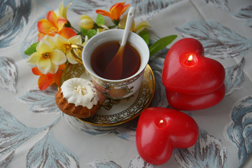 On a wooden table, tea Cup, creamer, flowers in a vase, kettle, marmalade and cakes. Breakfast on...