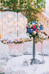 Table set for wedding or another catered event dinner. Decoration arch flowers gift box.