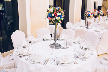 Table set for wedding or another catered event dinner. Decoration arch flowers gift box.